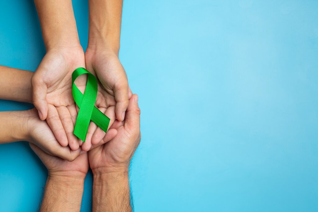 world mental health day green ribbon put human s hands blue background - Setembro Verde: a importância da informação para doação de órgãos