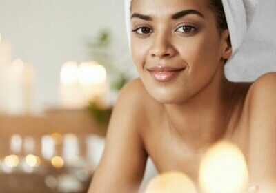 Portrait of beautiful african girl with towel on head smiling looking at camera resting in spa salon.
