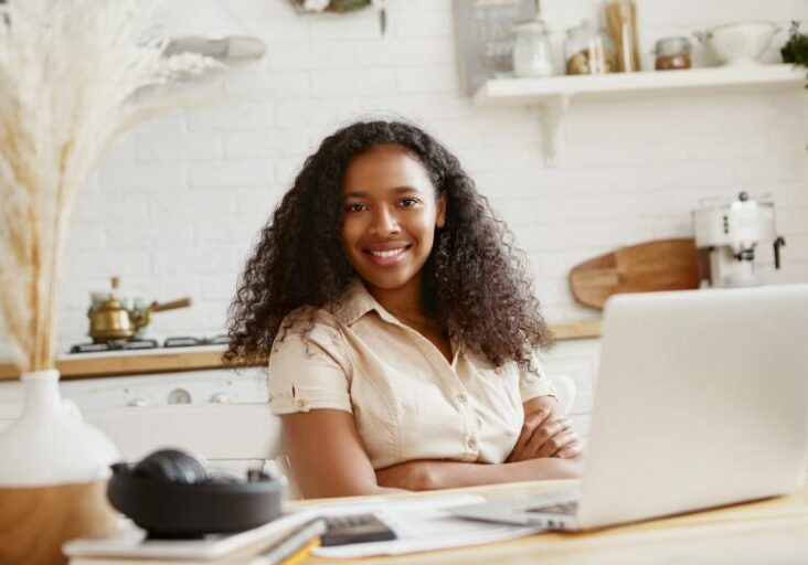picture-cute-stylish-young-african-american-woman-accountant-with-confident-toothy-smile-working-remotely-laptop-computer-doing-finances-kitchen-technology-occupation-freelance
